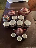Lot showing all items together: one tall teapot, one mini teapot, two sugar bowls (one with handle), 3 mini teacups ~2 inches, 22 teacups ~3 inches wide.