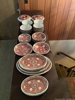 Overall arrangement of stacks of red Famille Rose bowls, dishes and platters on a table