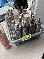 Photo of 28 assorted Bath & Body Works spray bottles in a grey basket with visible metallic and floral designs, various spray top colors.