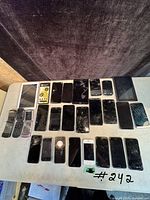 Overview of the lot displaying approximately 23 devices including tablets, flip phones, feature phones, and smartphones with cracked screens.