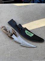 Cutting tool with bronze dragon handle and protective black sheath, showing overall length and shape.