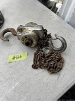 Close-up image of the metal chain hoist showing the hoist body, rusted chain, and two metal hooks.