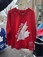 Front view of red Team Canada sweater showing large white maple leaf and 'CANADA' text