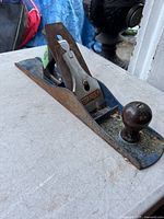 Vintage Stanley hand planer with visible wear, rust, wooden knobs, and Stanley branding on the blade housing.