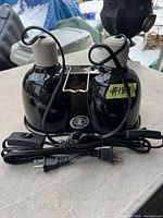 Zoo Med double light lamp, black housing with two light sockets with power cords and on/off switches, front view.