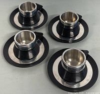 Four espresso cups with matching saucers, top view on gray surface
