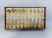 Set of five gold teaspoons and five matching gold forks arranged in original box with white satin lining.