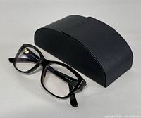 Gucci eyeglasses placed in front of black Prada sunglasses case on white background.