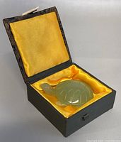 Jade turtle displayed inside the yellow lined original box showing the turtle and the box interior.