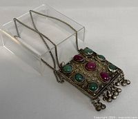 Front angle view of pendant necklace showing green and red agate stones with silver bead tassels.