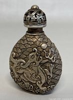 Front view of the snuff bottle showing dragon design and textured background.