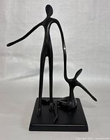 Front view of the black metal sculpture showing the two abstract dancer figures on the base.