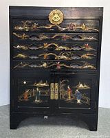 Front view of the black lacquer chest featuring hand-painted scenes and mother of pearl inlays with brass lock plate and handles.