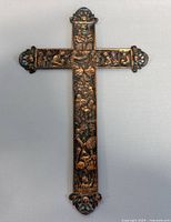 Front view of vintage copper wall cross showing detailed raised relief designs and ornate ends.