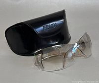 Photo of vintage Fendi rimless sunglasses with gradient brown lenses alongside original black hard case with embossed Fendi logo.