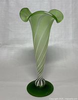 Front view of the green vintage hand blown art glass vase showing flared top with three rounded petal extensions and spiral white swirl pattern down to green circular base.