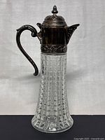 Front view of vintage cut crystal wine pitcher with silver-plated neck and handle
