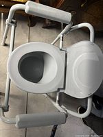 Top view of the commode showing the seat with padded armrests and open plastic lid.