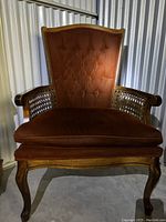 photo of red velvet brown wooden armchair with tufted backrest and cane detail sides