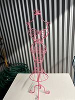 Front view of pink wire dress form jewelry holder showing full shape and structure.
