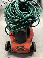 Top view of orange Black & Decker electric lawnmower with reversible handles, visible signs of use.