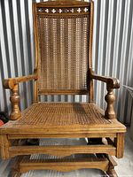 Front view of the solid brown wicker rocking chair showing woven backrest, seat, and sturdy wooden armrests and structure