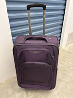 Front view of purple carry-on suitcase with 4 wheels and retractable telescopic handles.
