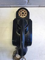 Top view of antique black church intercom with rotary dial and handset resting on unit, showing black finish, handset, and rotary dial clearly.