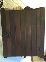 Front view of antique wooden corner cabinet with vertical slat door and metal hinges showing overall condition and door design