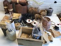 Overview of assorted leather supplies including rolled hides, coils of leather strips, and wooden box with smaller items.