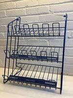 Front view of blue metal wire candy display rack with three tiers and candy brand names on each shelf.