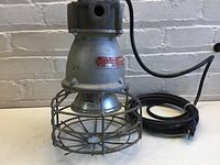 Front and side views of used Crouse Hinds industrial light featuring wire guard and electrical cord with plug. Shows condition and configuration.