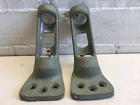 Pair of green painted metal flag holders positioned side by side showing front and top