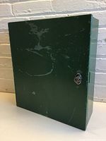 Front view of heavy green metal cabinet showing scratches and lock.