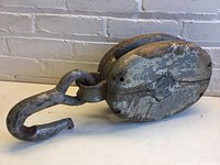 Side view of the entire pulley showing the full wooden body and metal hook.