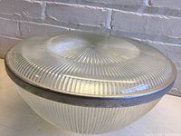 Side angle of the large round ribbed glass Holophane globe with metal rim showing the banded glass texture and dome shape.