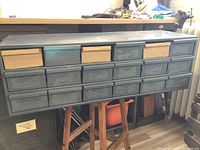 Front view showing metal parts bin unit with four cardboard drawers in the top row and metal drawers in lower rows.