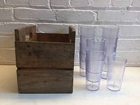 Photo of 12 clear plastic tumblers with pebble texture next to wooden crate.