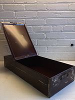 Vintage metal safety deposit box open showing interior and lid.