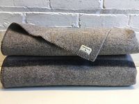 Two folded vintage wool blankets stacked, grey with visible black band, showing overall condition.