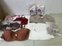 Full view of assorted bras laid out on table showing various colors, styles, and packaging including Playtex 18 Hour bras.