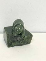 Side view of dark green jade bear figurine on base