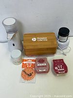 Photo of white Lysol soap dispenser, wooden Empire Life Vie box, two white candles, black small candle, and three packets of wax melts.