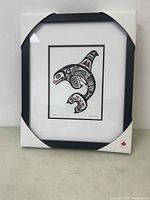 Photo of framed indigenous art print in original packaging with visible Canadian heritage symbol.