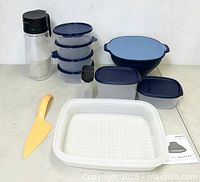 Full view of the lot containing all the Tupperware items described, showing the bottles, cutting tool, stack of containers, mixing bowl, and large container.