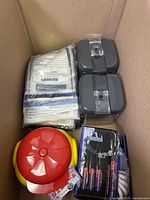 Box containing two grey plastic lidded containers, red and yellow carousel-shaped item, and other packaged items.