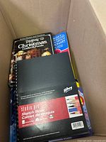 Box showing a black Klutz Studio Pro Sketch Book along with Christmas crafts book and English-French dictionary visible beneath.
