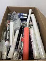 Cardboard box with various rolled posters or paper items and cylindrical packs