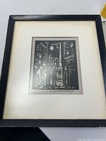 Framed black ink woodcut print showing street scene with men under street lamp, signed H.G. Prusheck.