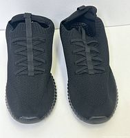 Top-down view of black slip-on running shoes showing breathable knit design and elastic laces.